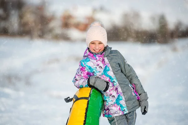 Fille avec traîneau à neige gonflable en descente en hiver — Photo