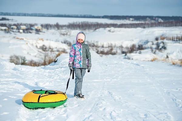 Fille en vêtements de ski traîne tubing neige sur la colline — Photo