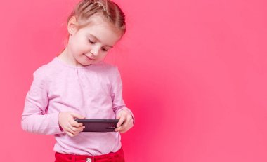 Sevimli kız pembe arka plan üzerinde Smartphone kullanarak