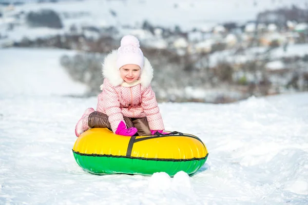 Kleines Mädchen sitzt auf Schneeröhre — Stockfoto