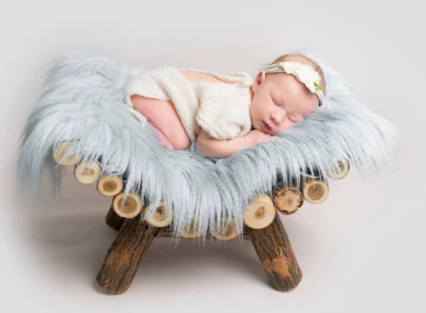 Bébé fille nouveau-né dort sur un petit lit en bois . — Photo