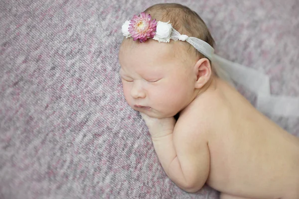 Nyfödd flicka sover på hennes sida i blomma hårband, närbild — Stockfoto