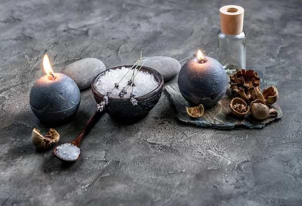 Bowl of spa salt and candles on grey background