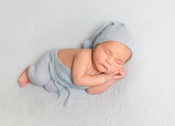 Junge auf weißer Decke zusammengerollt — Stockfoto