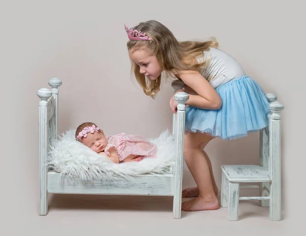 Little girl sits next her newborn sister — Stock Photo, Image