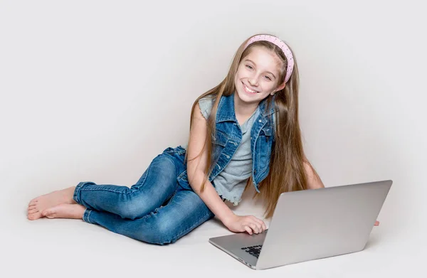 Litlle flicka liggande på golvet med laptop — Stockfoto