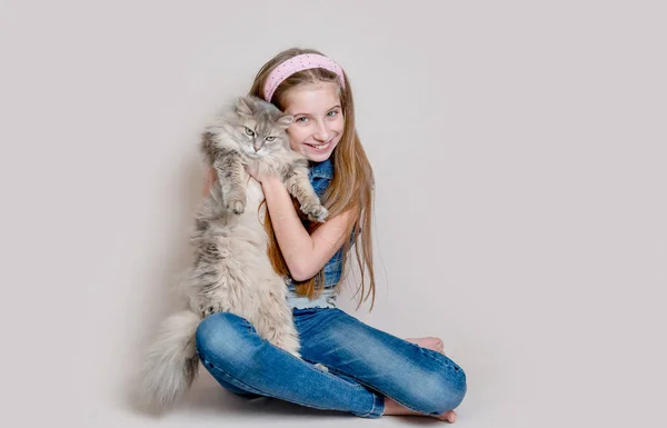 Ragazza positiva che gioca con il gatto su sfondo grigio — Foto Stock