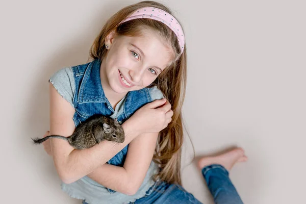 Lächelndes kleines Mädchen mit einem Deguu auf dem Arm — Stockfoto