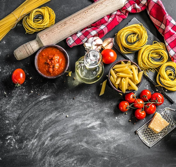 Koyu arka plan üzerinde ham makarna çeşitleri türleri — Stok fotoğraf