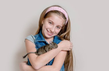 Küçük kız bir degu kollarında tutmak gülümseyen