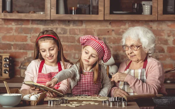 Grandma and granddaughters spreading dough — Stock Photo, Image