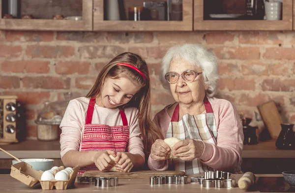 Mulher idosa ensinando uma menina a assar biscoitos — Fotografia de Stock