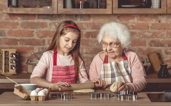 Mulher idosa ensinando uma menina a assar biscoitos — Fotografia de Stock