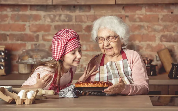 Malá vnučka s babičkou těší domácí ovocný koláč — Stock fotografie