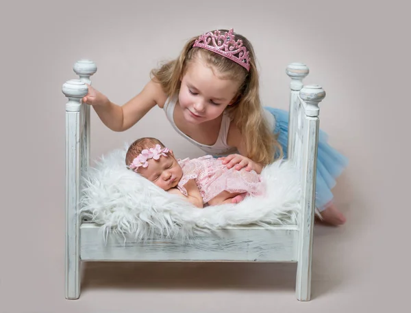 Little girl with her cute newborn sleeping sister — Stock Photo, Image