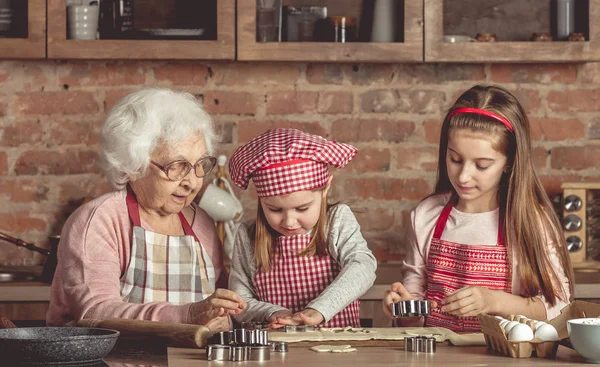 Little granddaughters help granny to bake cookies — Stock Photo, Image