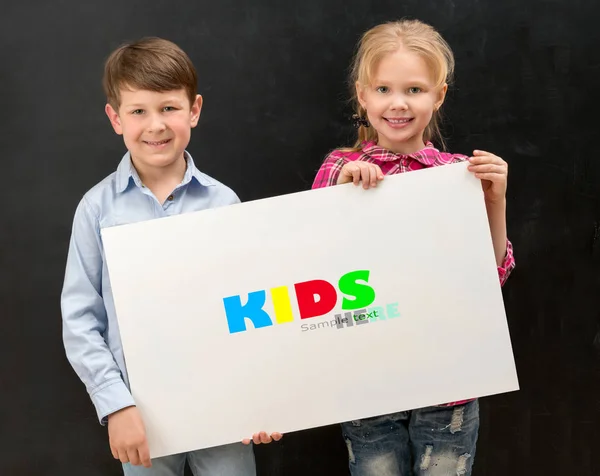 Two smiling schoolchildren with blank sheet of paper — Stock Photo, Image