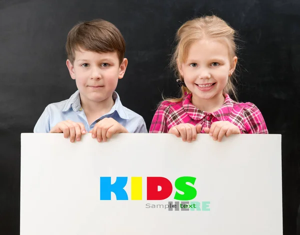 Dos escolares sonrientes con hoja de papel en blanco — Foto de Stock