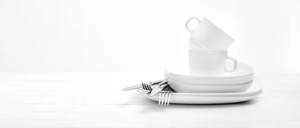 Πιάτα, ποτήρια και ασημένια μαχαιροπίρουνα σε ανοιχτό λευκό φόντο — Φωτογραφία Αρχείου