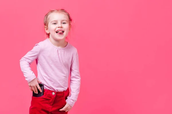 Bambina mostra la lingua e mette il suo cellulare in tasca — Foto Stock