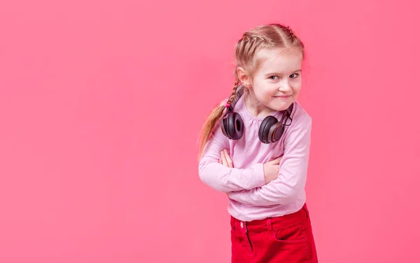 Petite fille dans les écouteurs sur fond rose — Photo