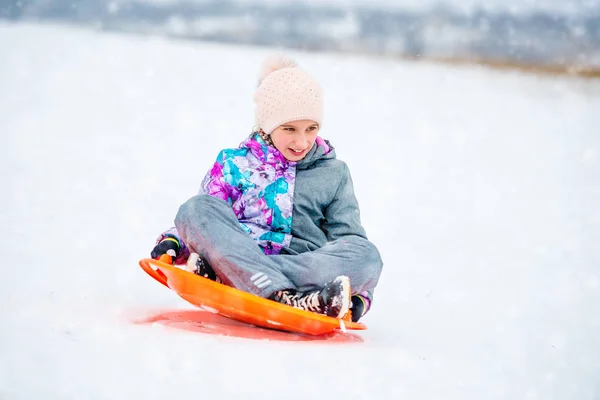 Meisje op schotel slee naar beneden de heuvel glijden — Stockfoto