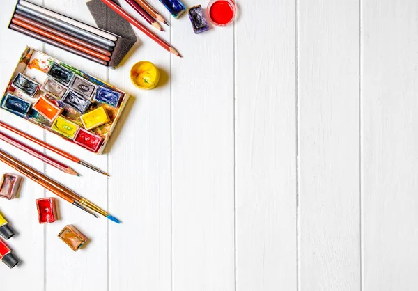 Brushes and paints with pencils on wooden background — Stock Photo, Image