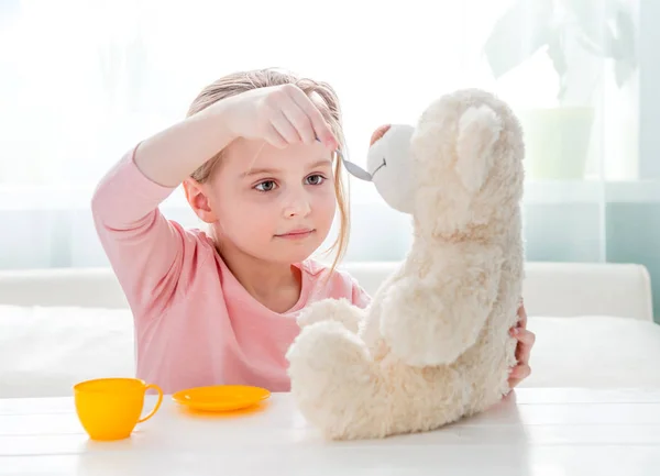 Bonito menina alimentando brinquedo ursinho — Fotografia de Stock