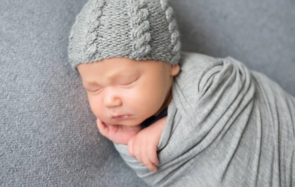 Nyfødte baby sovende krøllet op i gråt tæppe - Stock-foto