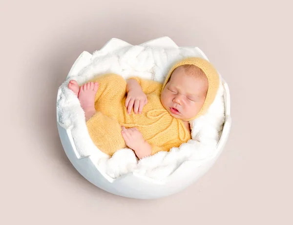 Sleeping newborn baby curled up on round basket