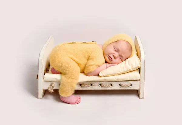 Baby gekleed in gebreide geel kostuum slapen op wieg — Stockfoto