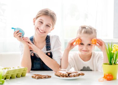 İki küçük renkli Paskalya yumurtaları tutan kız kardeş