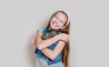 Küçük kız bir degu kollarında tutmak gülümseyen
