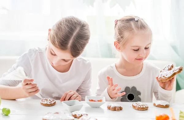 Roztomilé dívky zdobení velikonoční sušenky — Stock fotografie