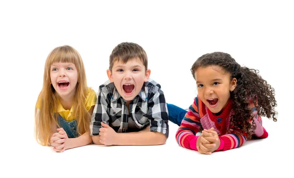 Drie grappige kinderen liggend op de vloer met open mond — Stockfoto