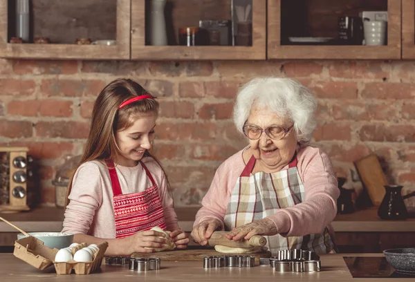 Mulher idosa ensinando uma menina a assar biscoitos — Fotografia de Stock