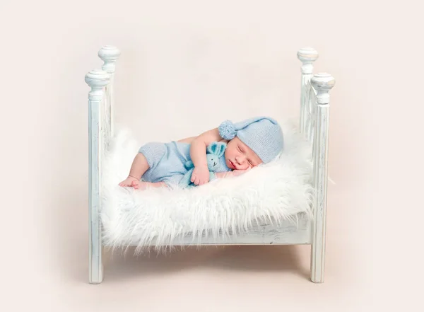 Nyfödd pojke i blå outfit sover på spjälsängen — Stockfoto