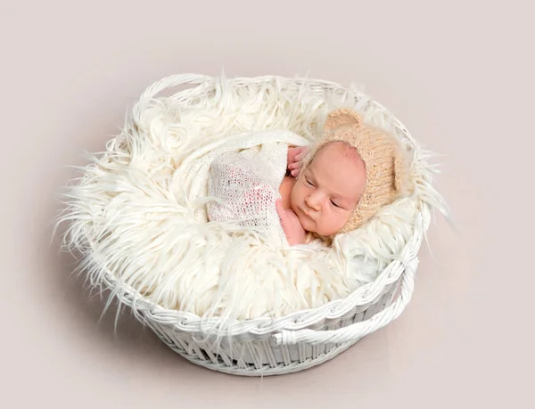 Новорожденный ребенок в смешной шляпе дремлет в корзине — стоковое фото