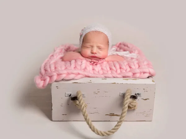 Bebê recém-nascido dormindo com bochechas gordinhas deitado na caixa no tapete — Fotografia de Stock