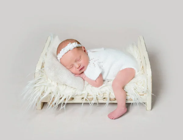 Lovely newborn baby sleeping on crib with leg on the floor — Stock Photo, Image
