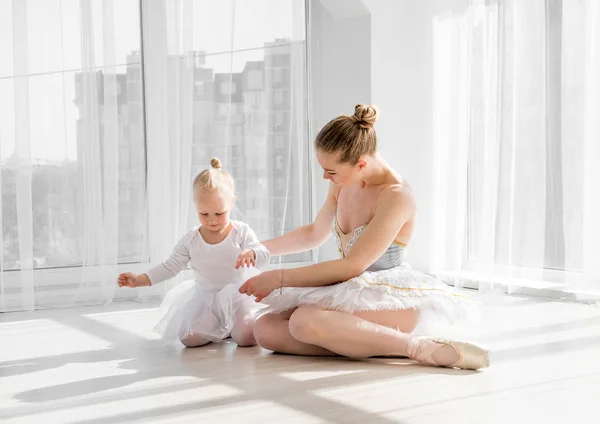 Μητέρα αγκαλιά με την κόρη που κάθεται στο πάτωμα στο στούντιο χορού — Φωτογραφία Αρχείου