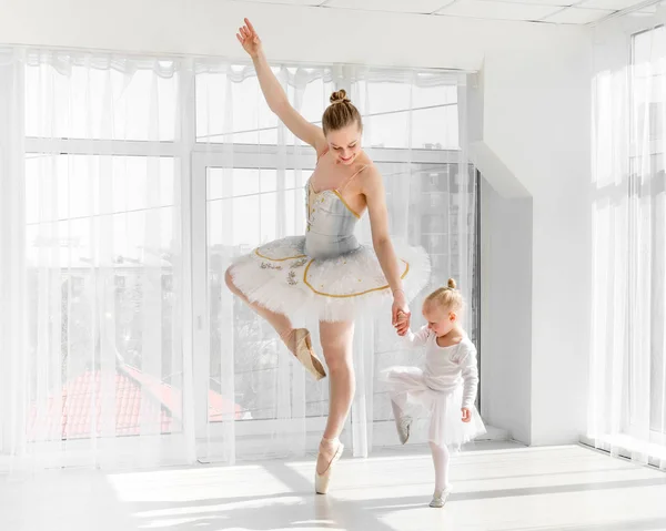Молода розкішна балерина зі своєю маленькою дочкою танцює в студії — стокове фото