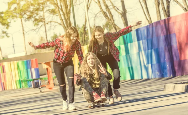 Les filles poussant ami sur le skateboard à la journée ensoleillée — Photo