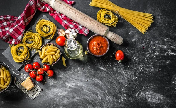 Různé typy surovin italské těstoviny na tmavém pozadí — Stock fotografie