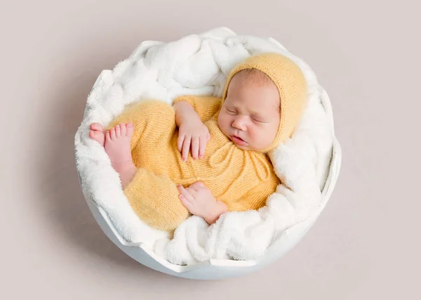Yuvarlak sepet üzerinde uyuyan yeni doğan bebek kıvrılmış — Stok fotoğraf