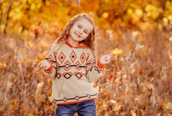 Söt flicka som håller gula blad — Stockfoto