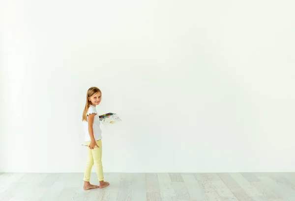 Menina pintura na parede branca dentro de casa — Fotografia de Stock