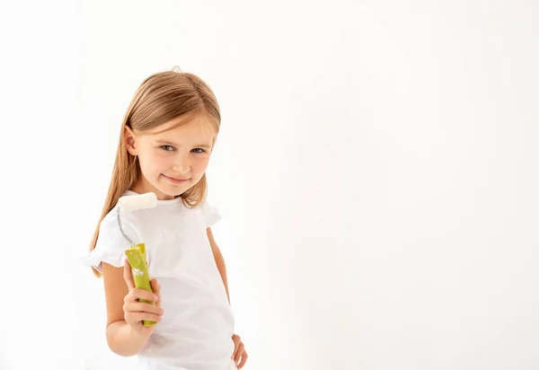 Küçük sevimli kız boya rulo ile bir duvar boyar — Stok fotoğraf