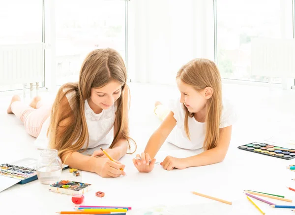 Дві маленькі сестри малюють на підлозі — стокове фото