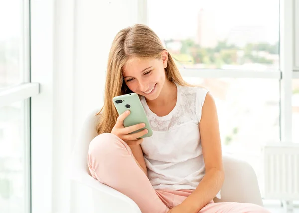 Teen girl spending leisure with her phone indoors — Stock Photo, Image
